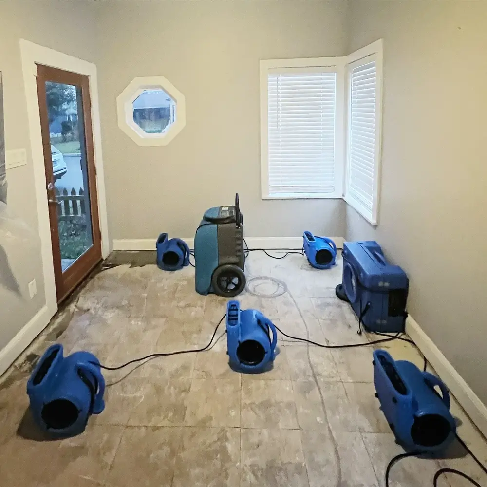 Air movers and dehumidifiers drying a floor after tile removal