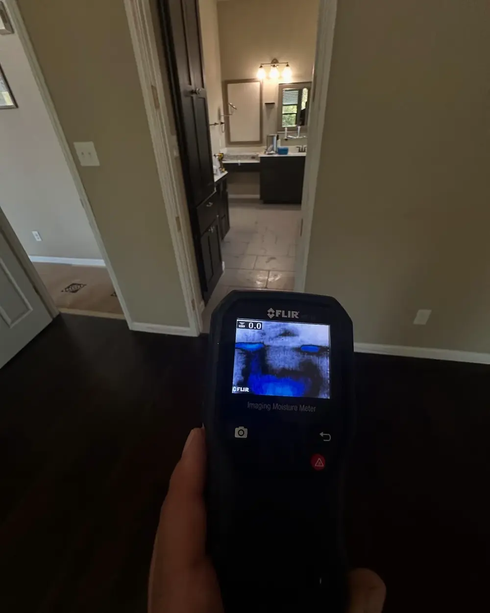 Technician scanning a wall with a FLIR thermal imaging camera
