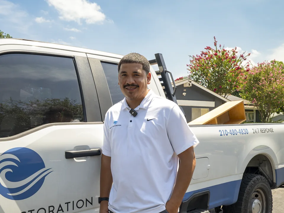 Jacob of Wavy Restoration in front of the company's branded trailer — water, mold and remodel, licensed and insured