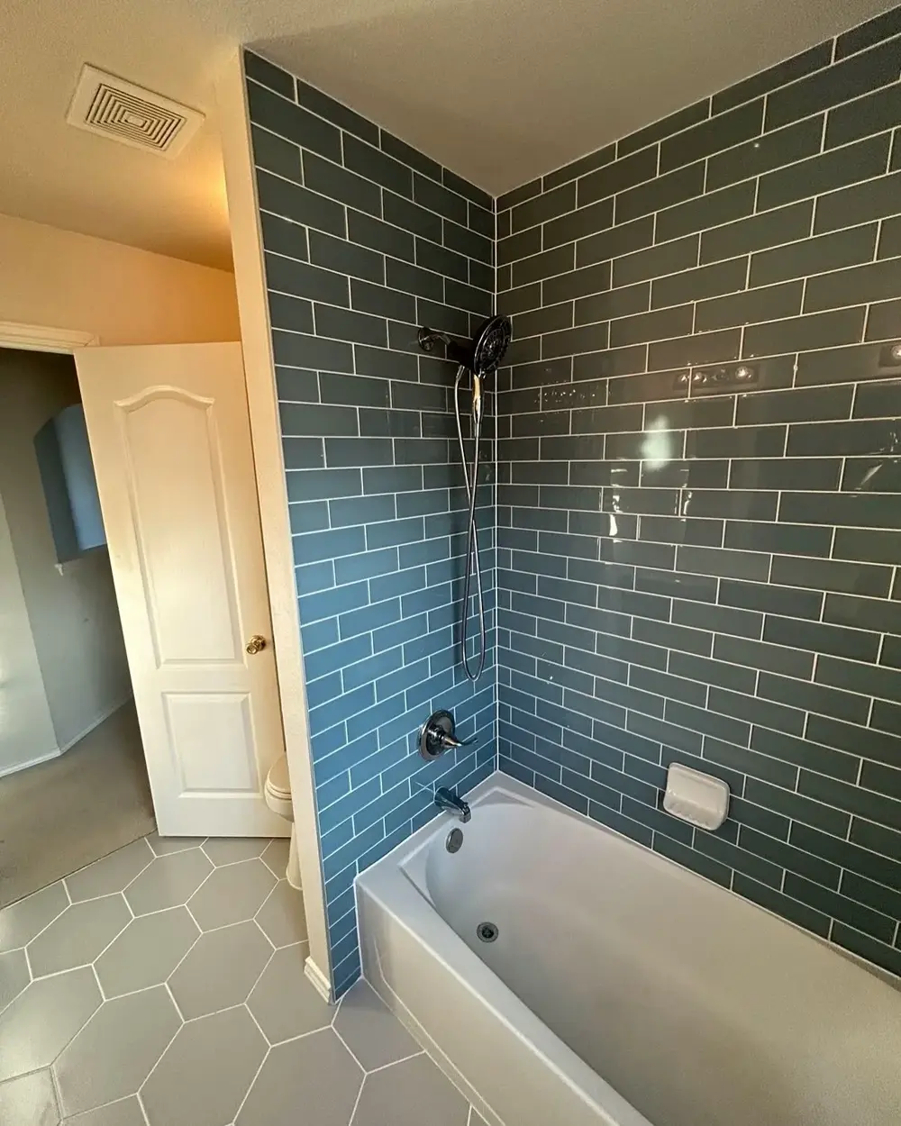 Finished bathroom rebuild — green subway tile tub surround and hex floor