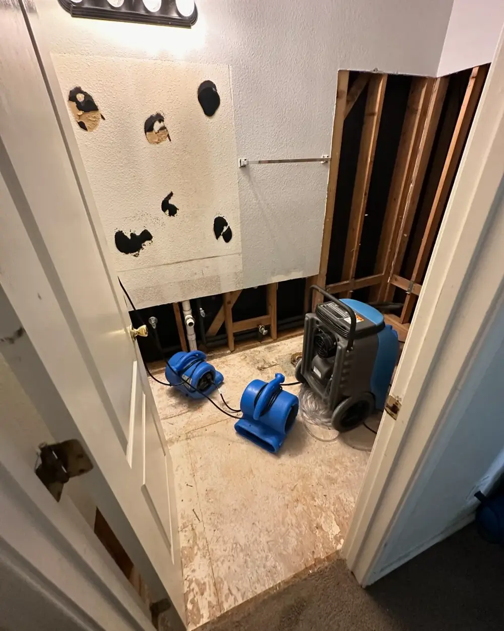 Bathroom opened to studs with drying equipment after a leak