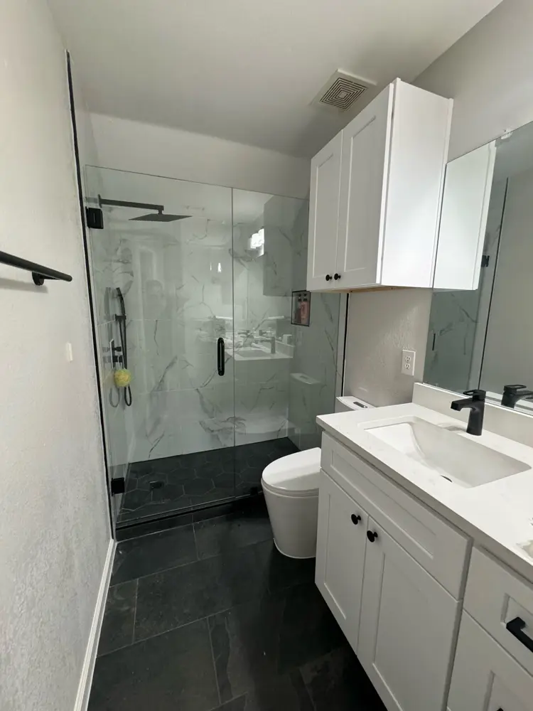 Finished bathroom — white vanity, black hardware, glass shower