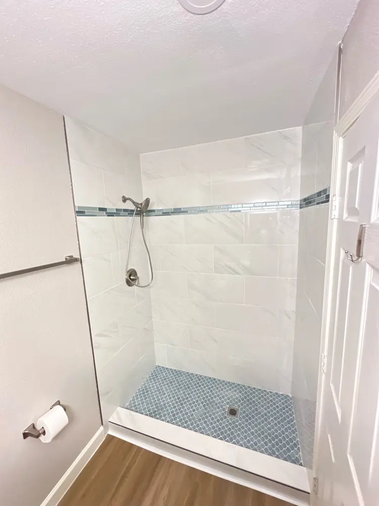 Finished shower with marble-look tile and pebble pan