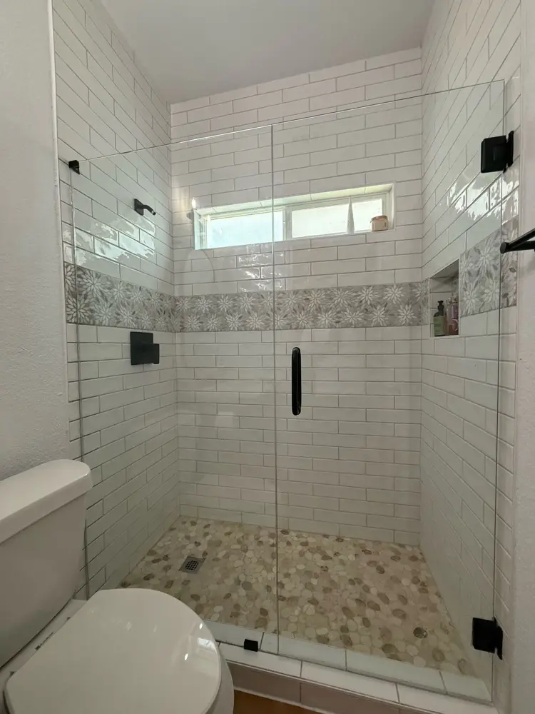Finished shower — white subway tile with pebble floor