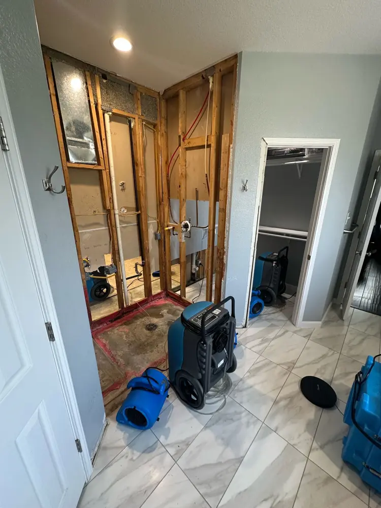 Shower wall opened to studs with drying equipment running