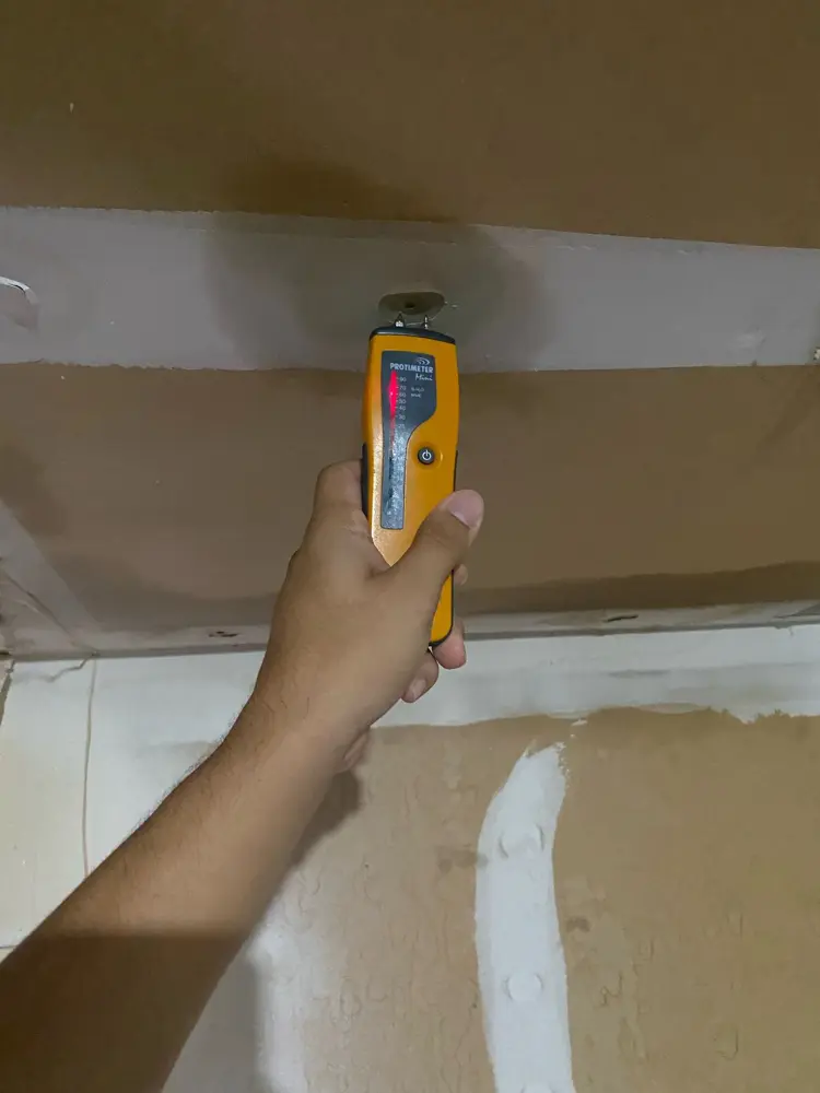 Moisture meter confirming a wet ceiling before drying